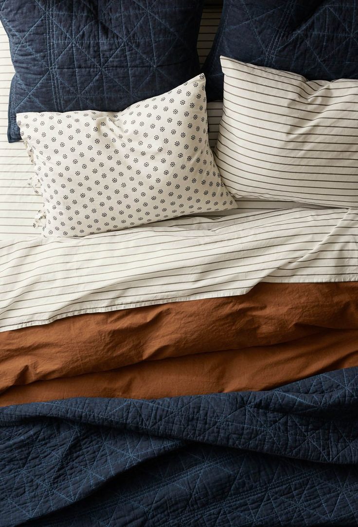 an unmade bed with blue and brown sheets