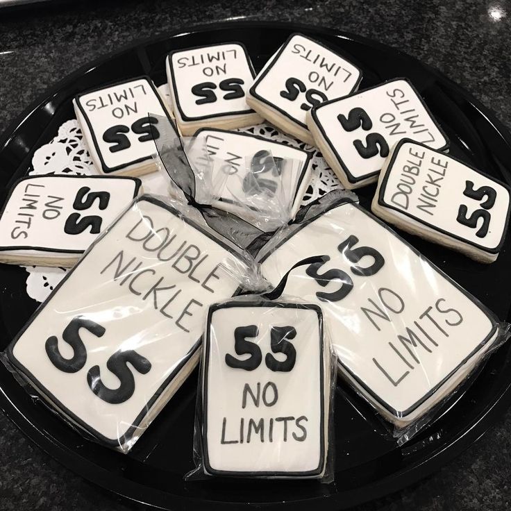 a black plate topped with lots of cookies covered in white frosted icing and numbers