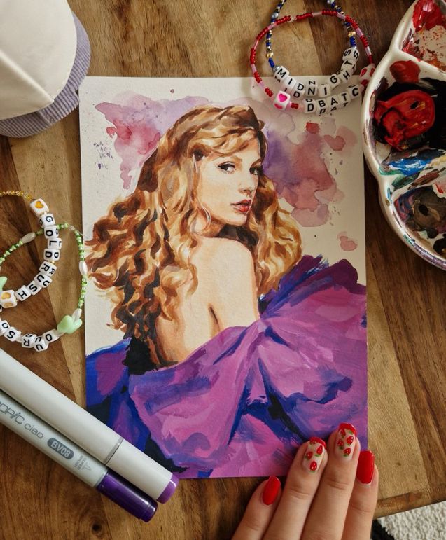 a woman's hand holding onto a painting next to other items on a table