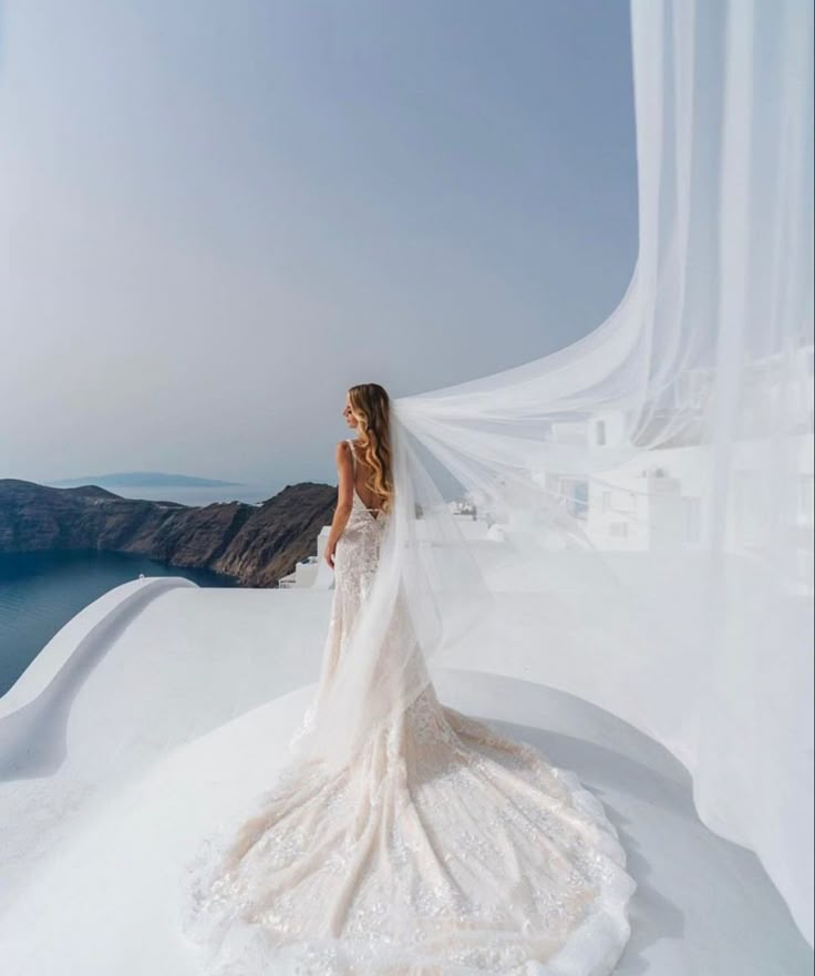 a woman in a wedding dress standing on top of a hill