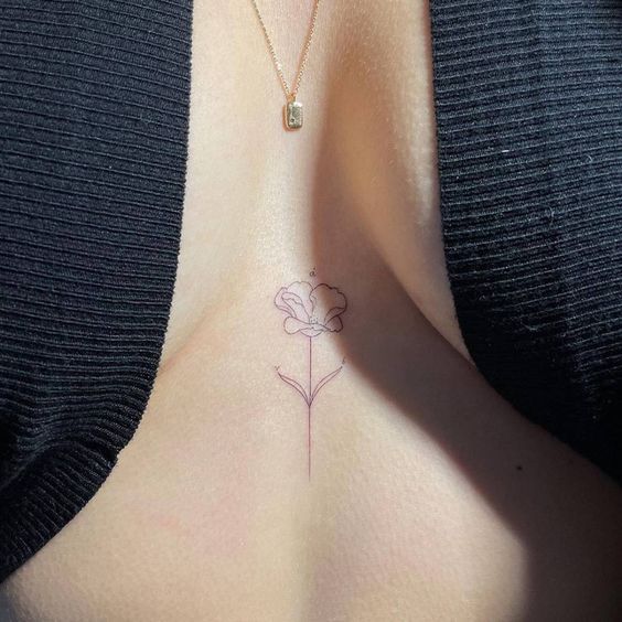 a woman's breast with a small flower tattoo on her left side ribcage