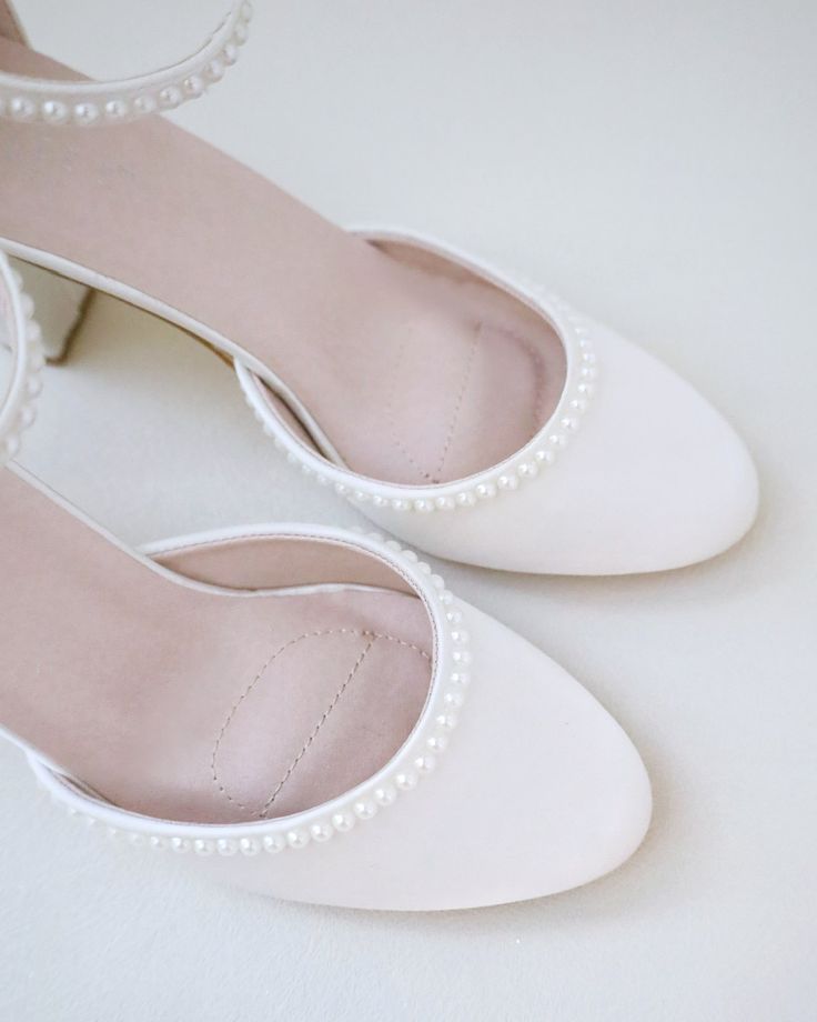 a pair of white shoes with pearls on the toe and heel are sitting on a table