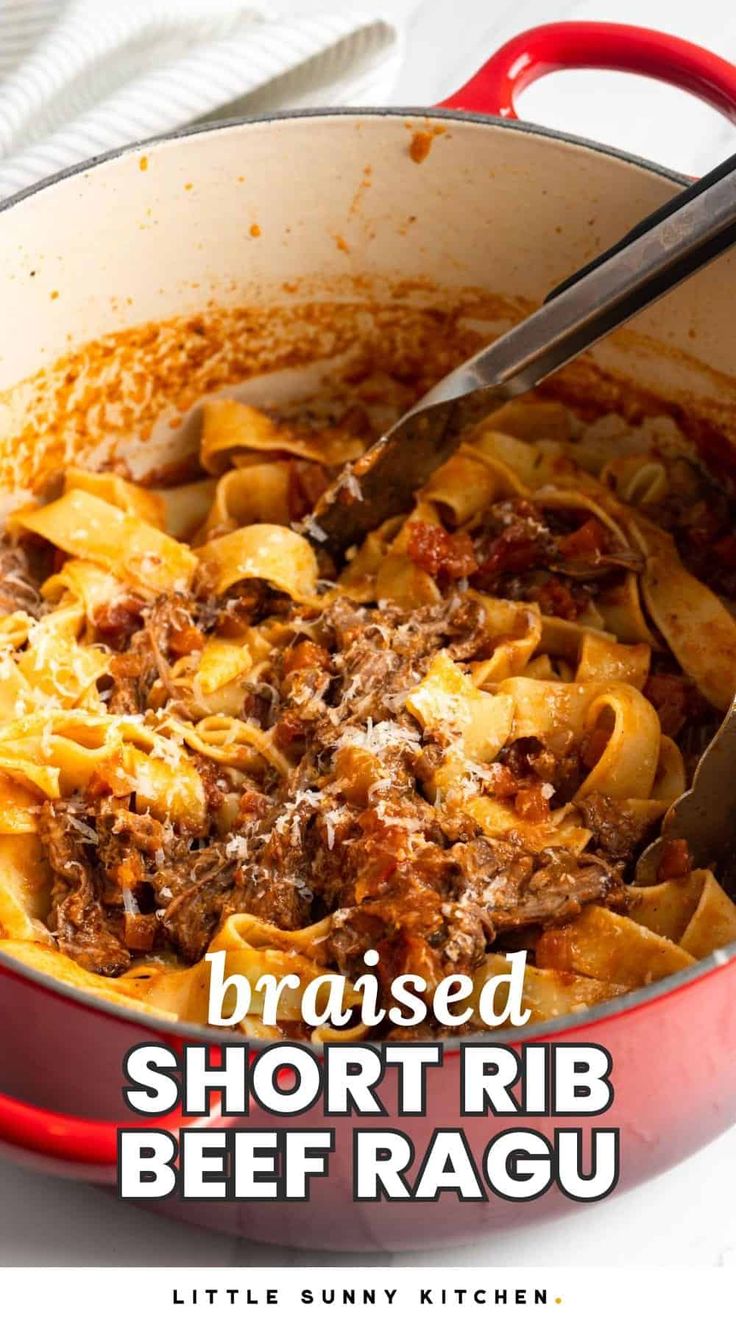 a red pot filled with beef ragu on top of a white tablecloth next to a knife