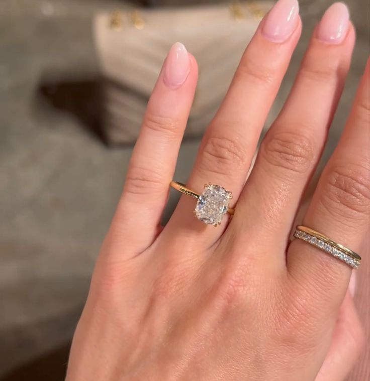 a woman's hand with two rings on it and a diamond in the middle