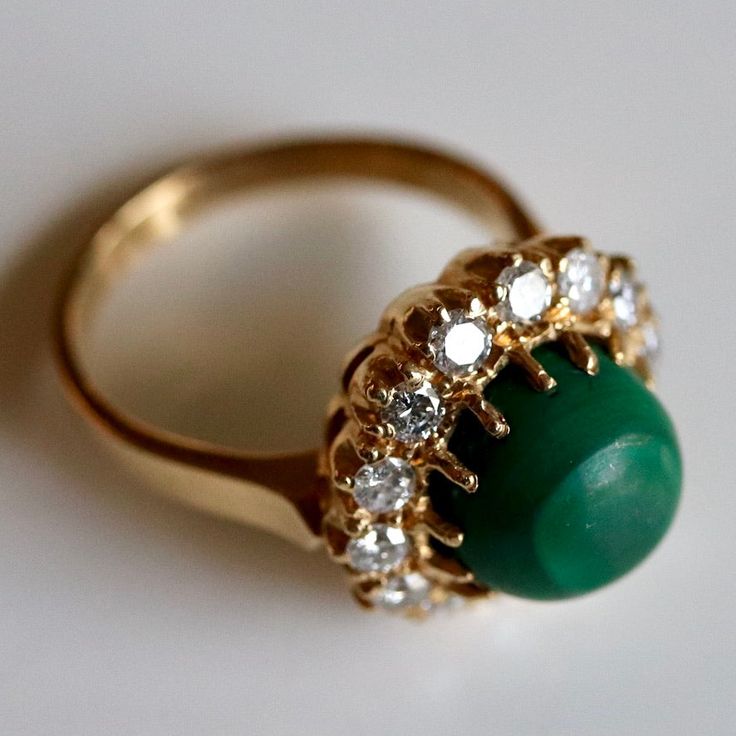 This Tudor design features 0.83 carats of diamonds encircling a malachite cabochon. Available in sizes 5-8. Elegant Green Dome Ring, Elegant Green Cabochons For Formal Occasion, Elegant Green Cabochon Emerald Ring, Elegant Green Emerald Cabochon Ring, Green Gemstone Cabochons For Formal Use, Elegant Green Gemstone Dome Ring, Green Gemstone Cabochons Fine Jewelry, Fine Jewelry Green Cabochons For Formal Occasions, Green Cabochons For Formal Fine Jewelry