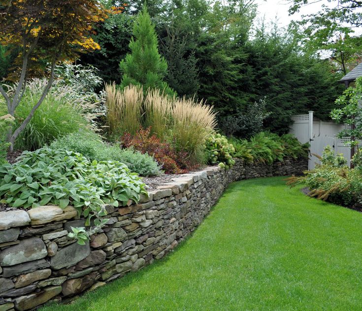 a stone wall in the middle of a garden