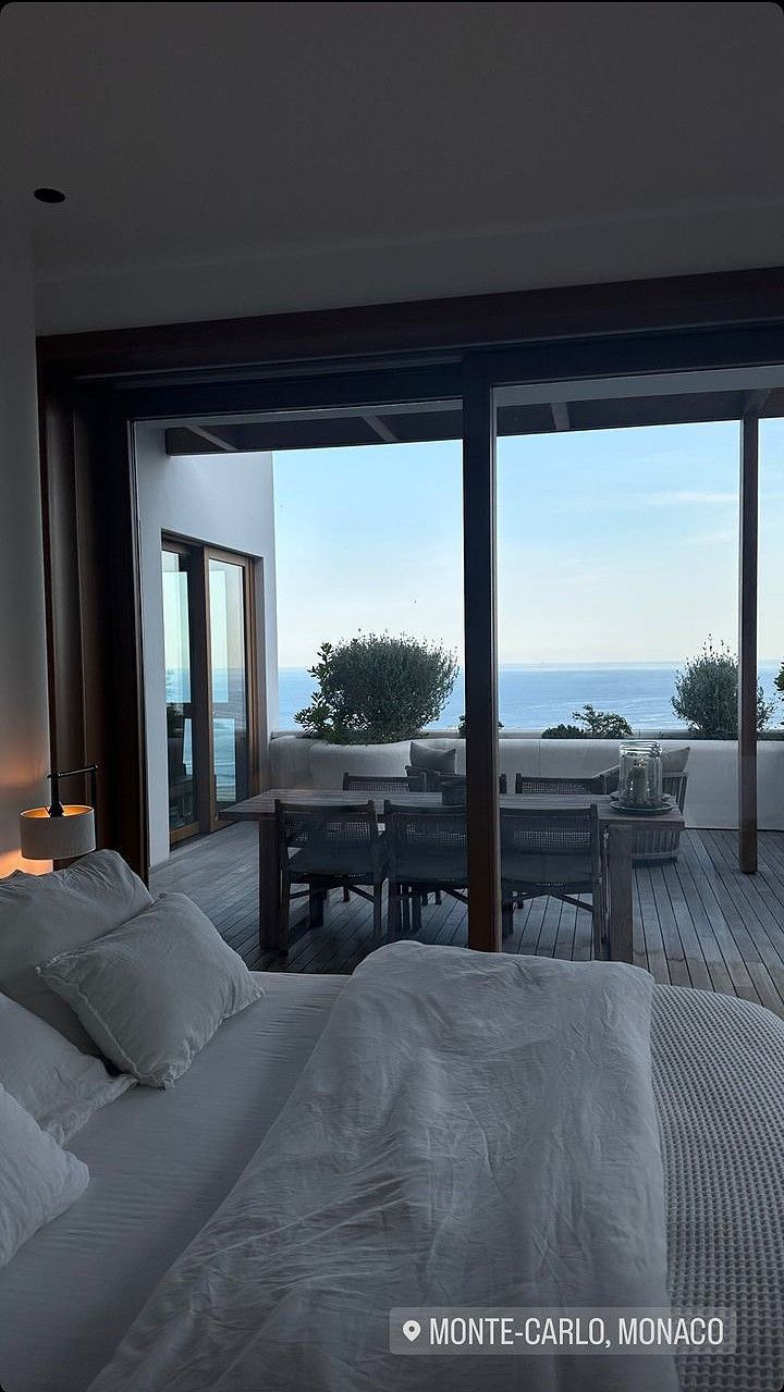 a large bed sitting in a bedroom next to a sliding glass door that leads out to the ocean