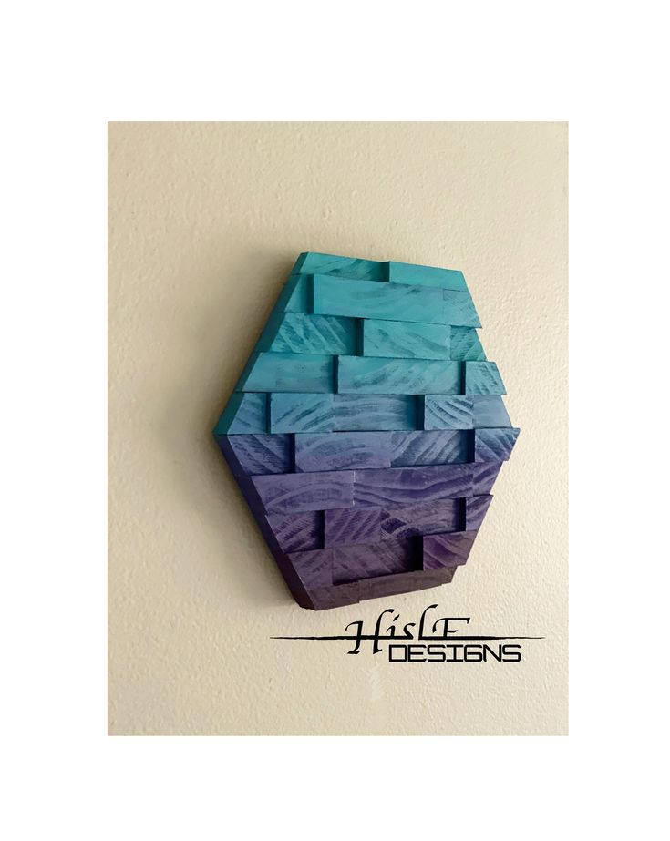 a blue and purple wall hanging on the side of a white wall with an abstract design