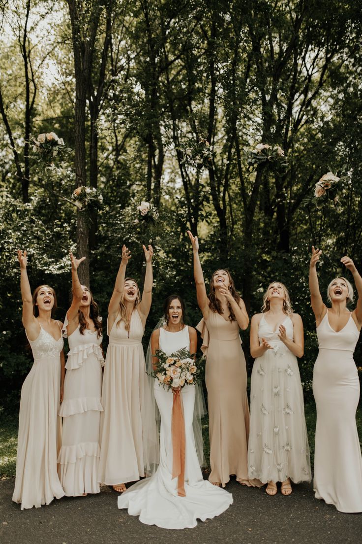 a group of women standing next to each other in front of trees holding their hands up