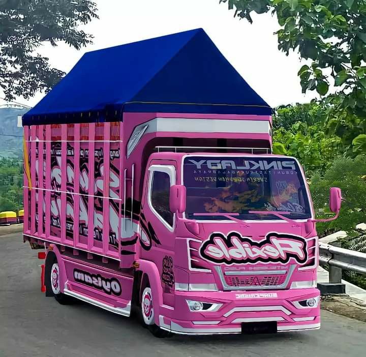 a pink truck is parked on the side of the road in front of some trees