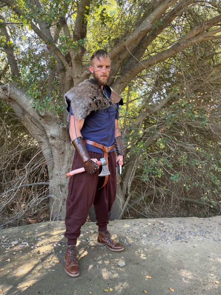 a man dressed in medieval garb standing next to a tree