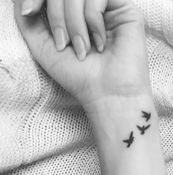 a woman's wrist tattoo with three birds on the left side of her arm