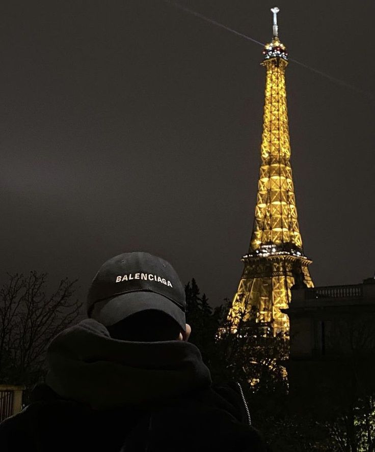 a man is looking at the eiffel tower lit up in yellow and black