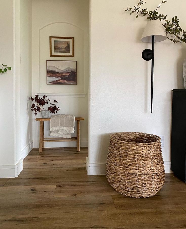 a basket sitting on top of a wooden floor next to a wall mounted tv and lamp