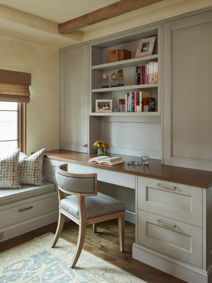 a home office with built in bookshelves, desk and window seat next to it