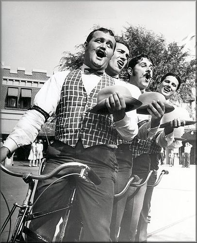 three men riding on the back of a bike with their mouths open and tongues out