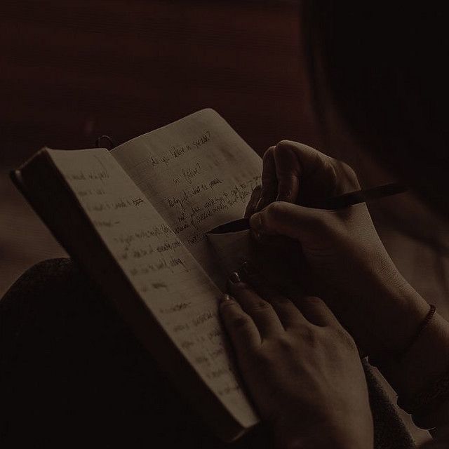 a person writing on a notebook in the dark