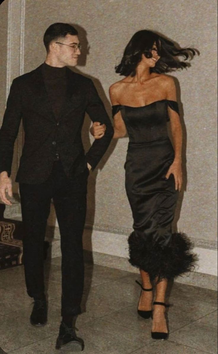 a man and woman dressed in black walking together