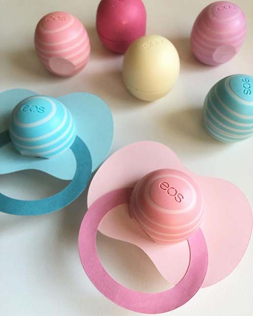 three pacifiers and several balls on a white table with pink, blue, and green shapes