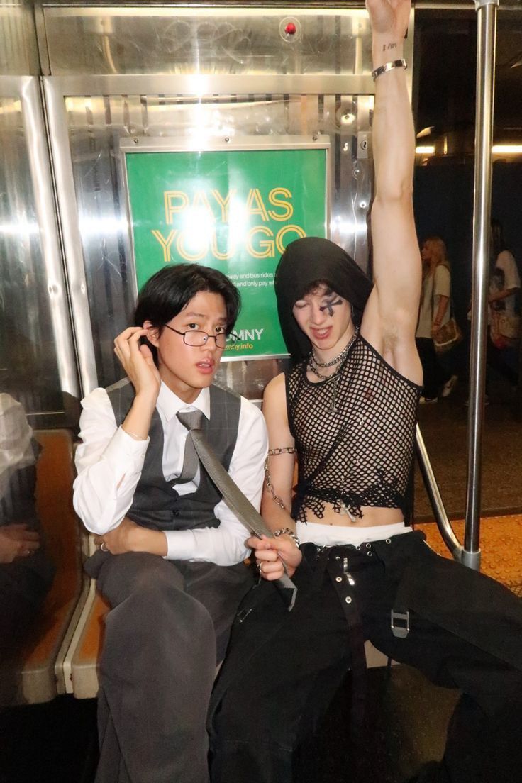 two people sitting on a subway car with one holding up the other's arm