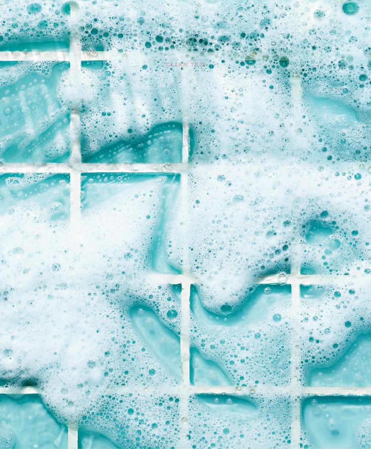 soapy water bubbles in front of a tiled wall with blue and white tiles on it