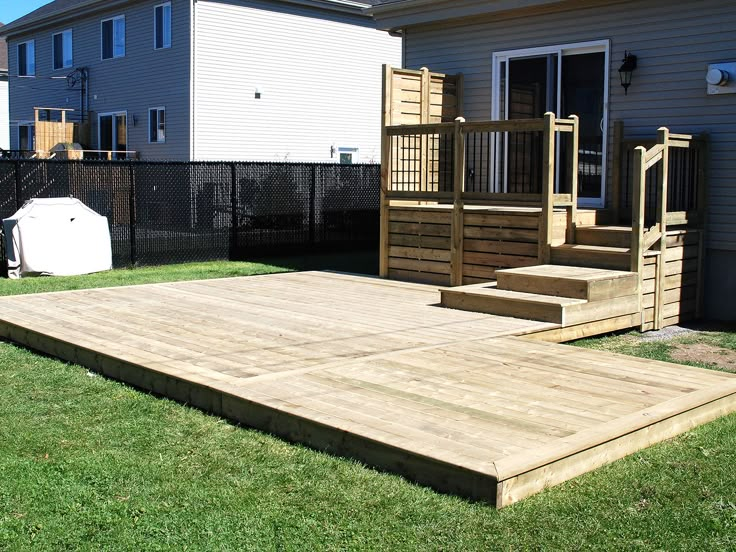 a wooden deck in the grass next to a house