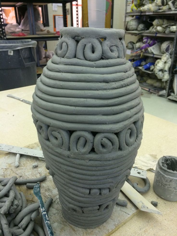 a large gray vase sitting on top of a table next to some metal chains and tools