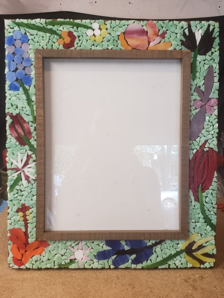 a wooden frame with flowers painted on the front and sides, sitting on a table