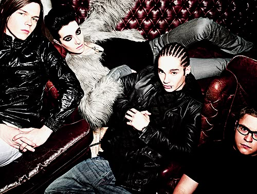 four people sitting on a couch with one person wearing glasses and the other in leather