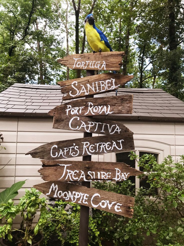 a wooden sign with several different signs on it in front of a house and trees