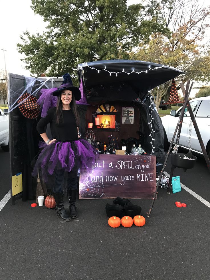 a woman dressed as a witch standing next to a sign