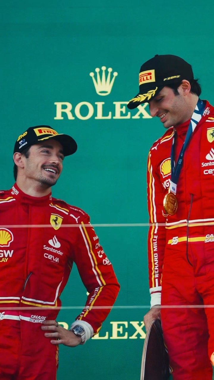 two men standing next to each other in front of a green wall