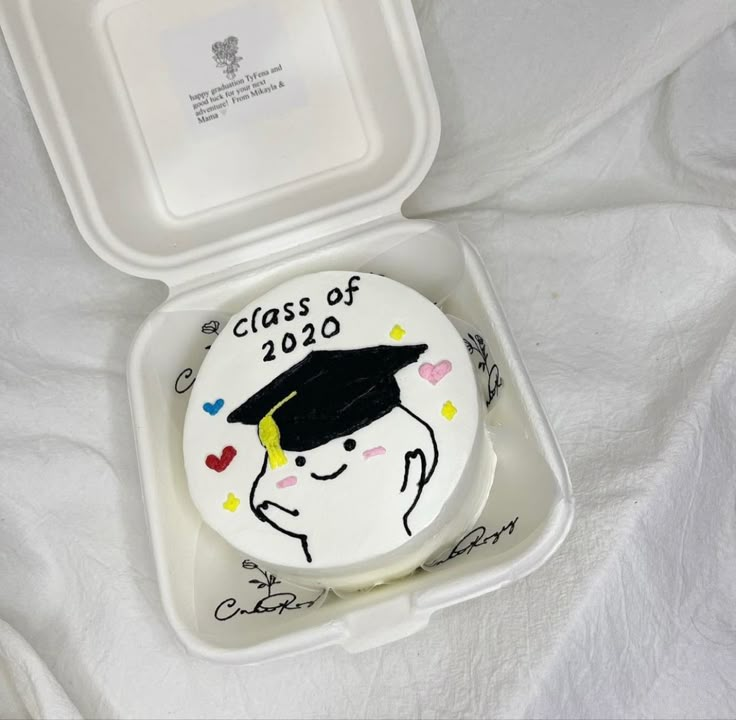 a graduation cake in a plastic container on a white sheet