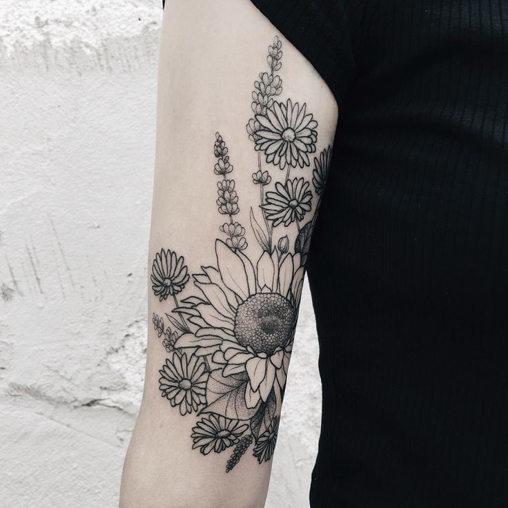 a woman's arm with black and white flowers on the left side of her arm