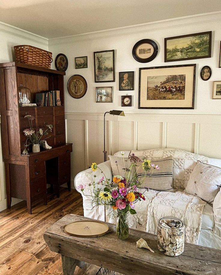 a living room filled with furniture and lots of framed pictures on the wall above it