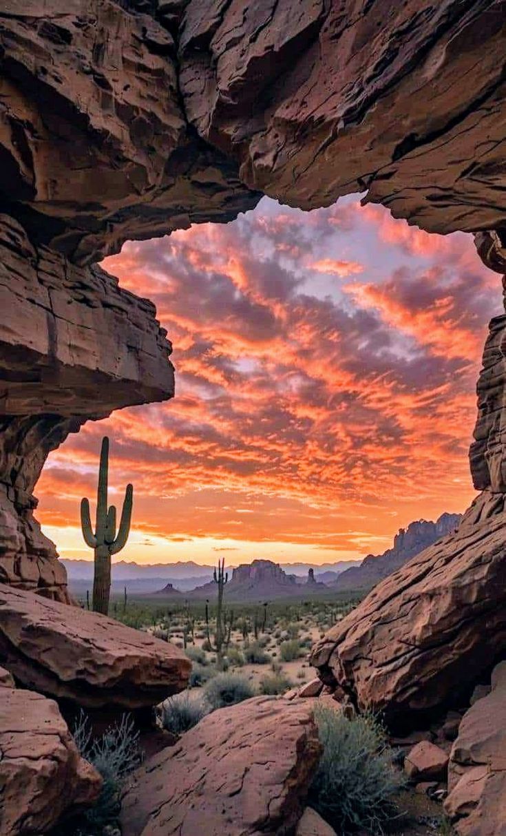 the sun is setting behind some rocks and cactus