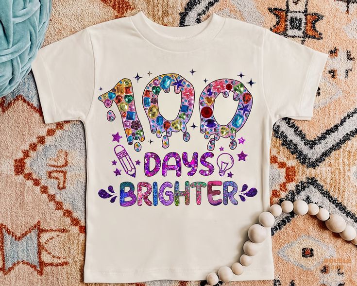 a t - shirt with the words 100 days brighter on it next to beads and other items