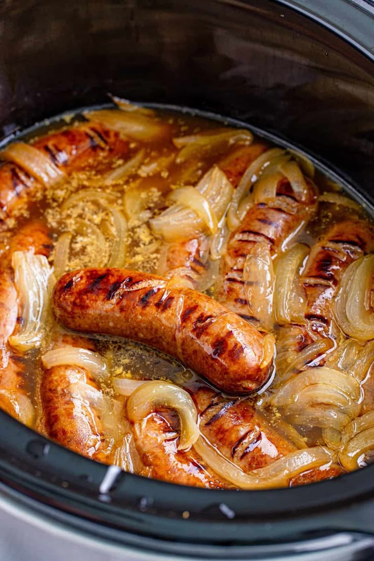 two sausages and onions are cooked in the slow cooker for an easy dinner