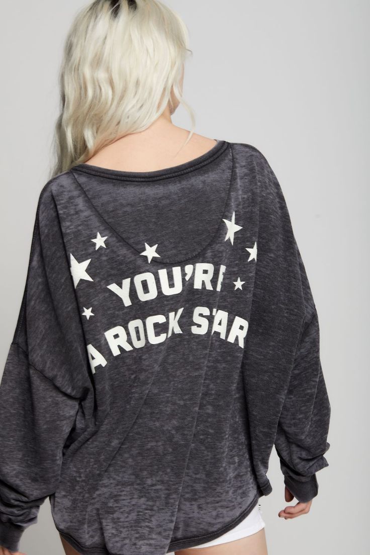 Show everyone what you are made of in style! This unique one size sweatshirt features a "Made Of Stars" disco ball graphic on the front with "You're A Rock Star" verbiage on the back. Made with soft vintage washed fabric, ribbed hems, a wide crew neckline, and a rounded high-low bottom hem for a relaxed, adaptable fit across various body types. This style features a one-size-fits-all design with stylish high-low hem details. Details Style #302264 Color: Black Made Of Stars One Size Long Sleeve S Relaxed Fit Sweatshirt With Star Print For Fall, Relaxed Fit Star Print Sweatshirt For Fall, Cotton Sweatshirt With Star Print And Relaxed Fit, Trendy Long Sleeve Star Print Sweatshirt, Grunge Style Text Print Tops For Fall, Trendy Crew Neck Tops For Music Festival, Trendy Distressed Long Sleeve Sweatshirt, Casual Star Print Sweatshirt For Loungewear, Trendy Distressed Long-sleeve Sweatshirt