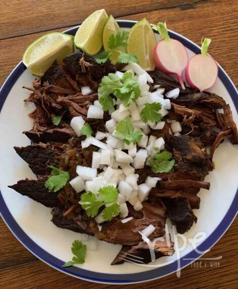 a white plate topped with meat, onions and cilantro