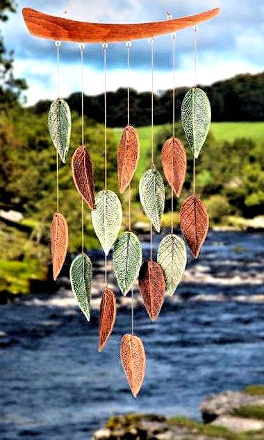 a wind chime with leaves hanging from it's side next to a river