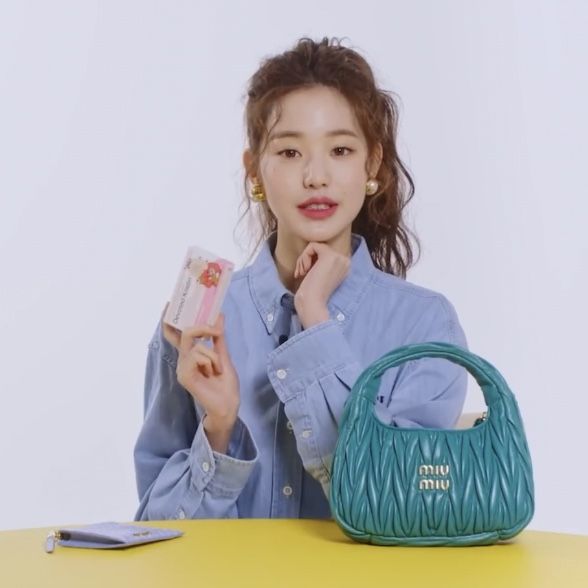 a woman sitting at a table with a green purse