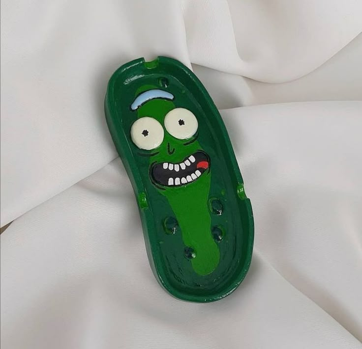 a green case with an evil face on it's side sitting on a white sheet