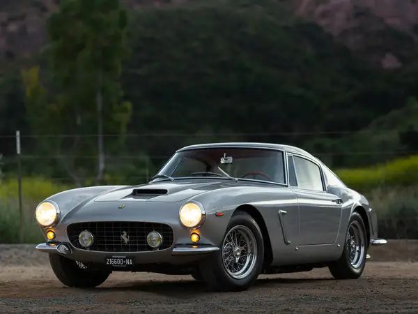 a silver sports car parked on top of a dirt field