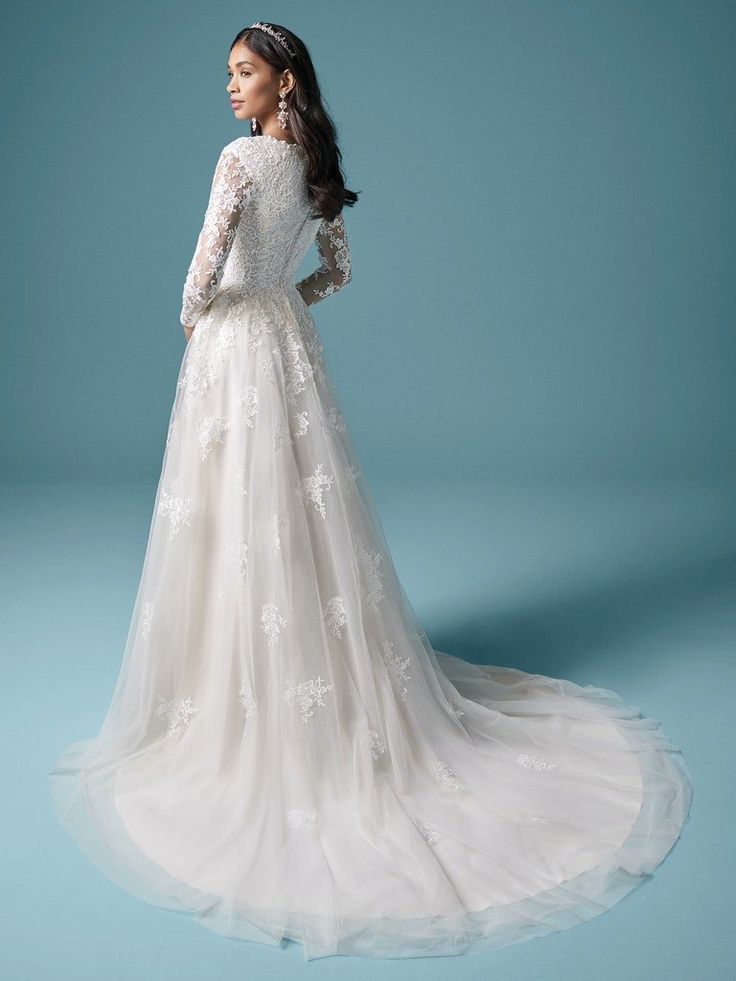 a woman in a white wedding dress is standing on a blue background with her back to the camera