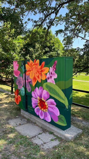 three colorfully painted wooden boxes sitting in the grass