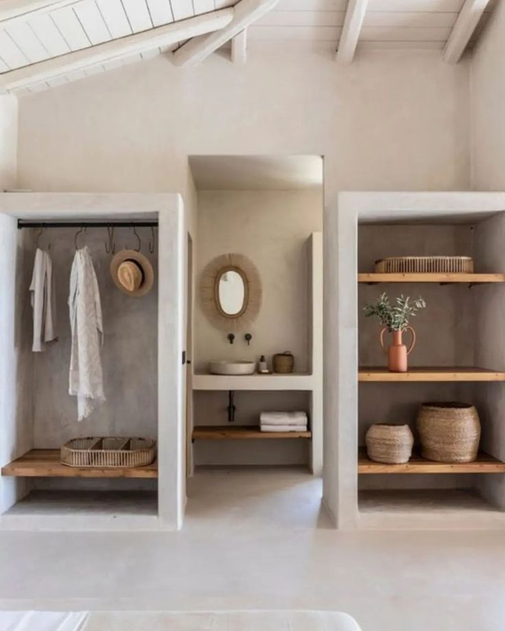 an open closet with shelves and baskets on the floor next to a bed in a white room