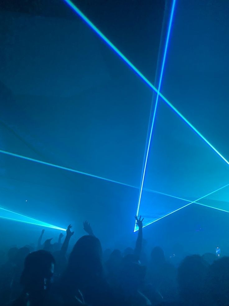 a group of people that are standing up with their arms in the air and some lights on