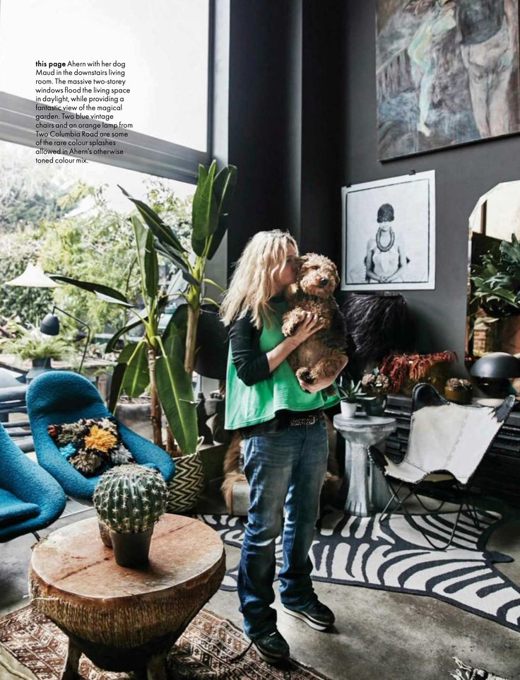 a woman holding a small dog in her arms while standing next to a cactus plant