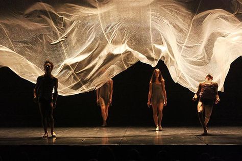 three people standing on a stage with white fabric covering them